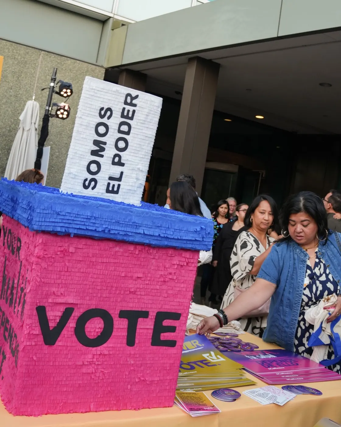 A ballot box piñata reading Somos El Poder at the welcome table