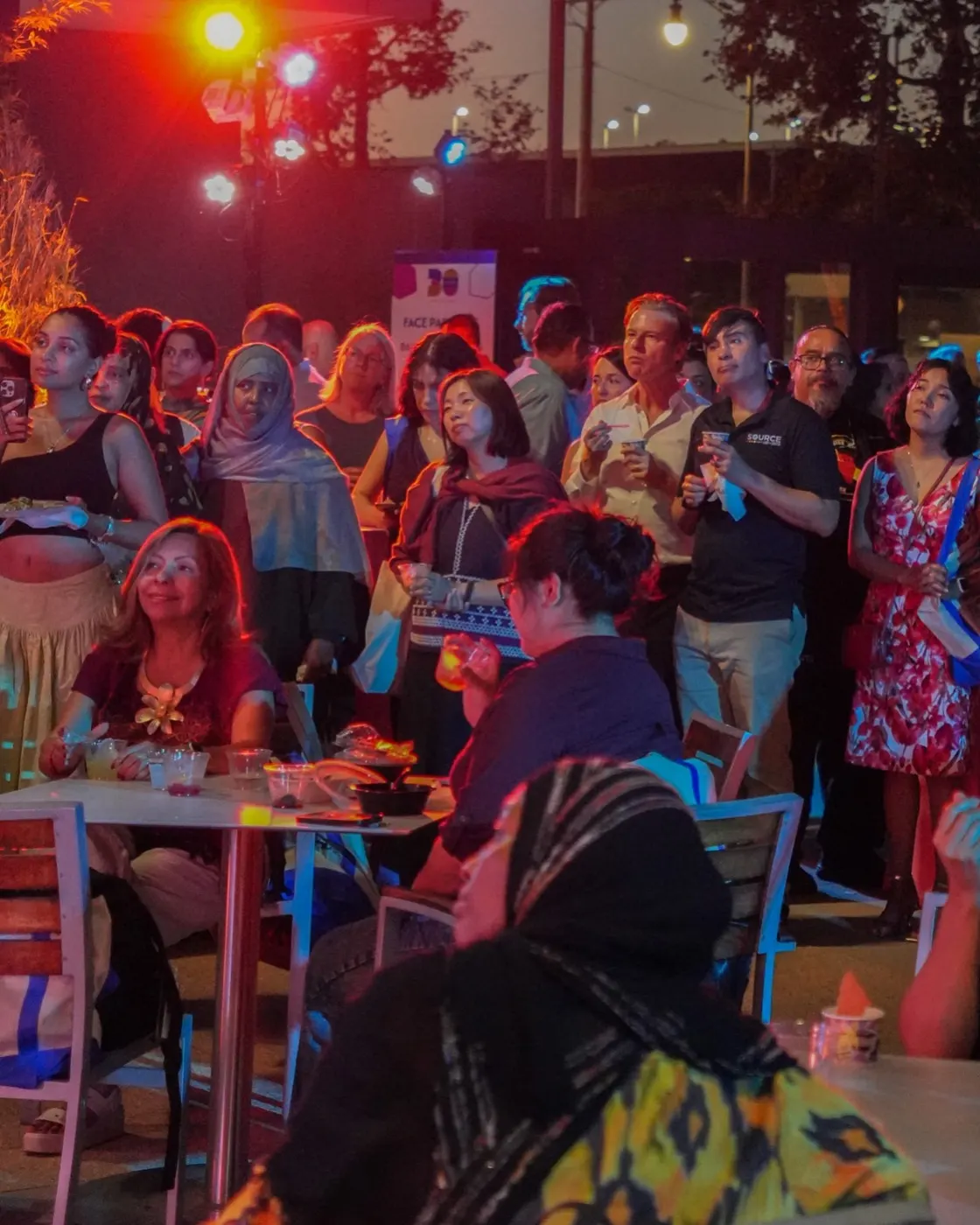 The crowd watches the program under the evening lights